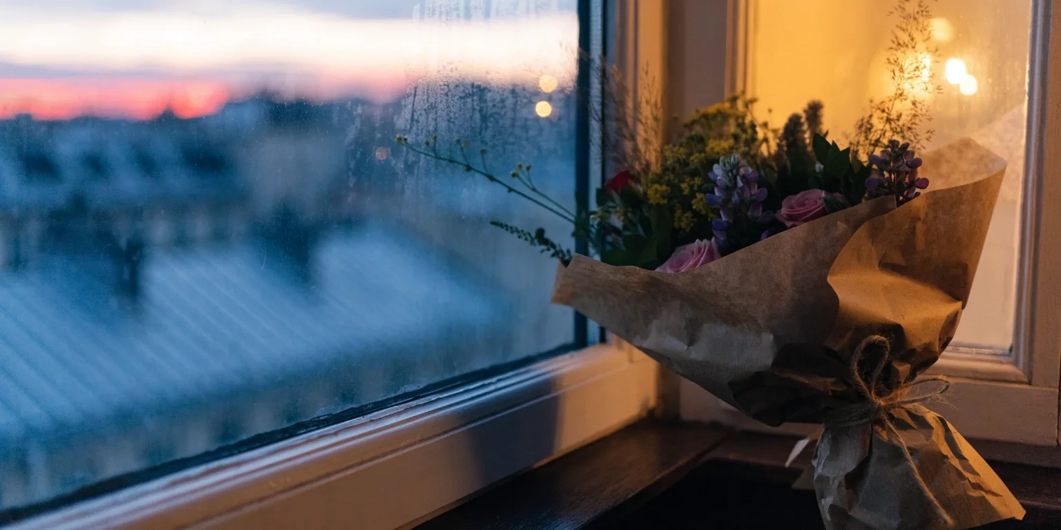 Bouquet posé sur un rebord de fenêtre parisienne au crépuscule